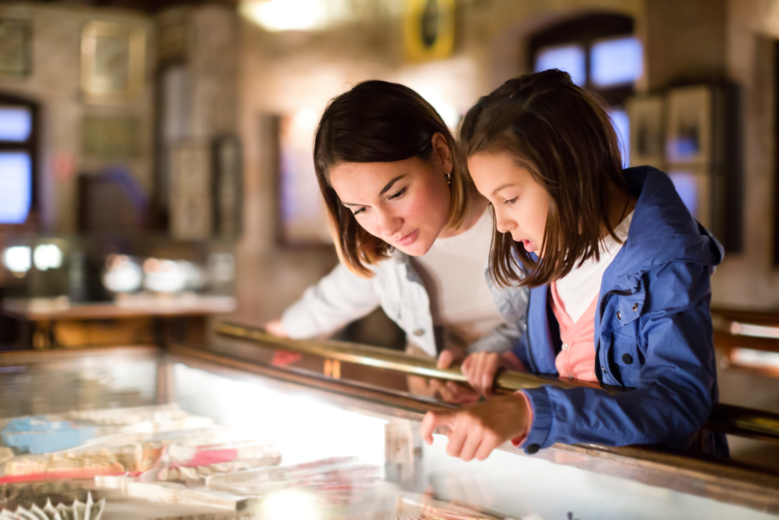 Adult and young girl exploring museum looking in display cabinet